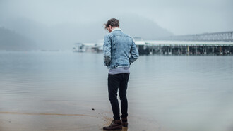 Man standing alone on the beach, looking at his reflection