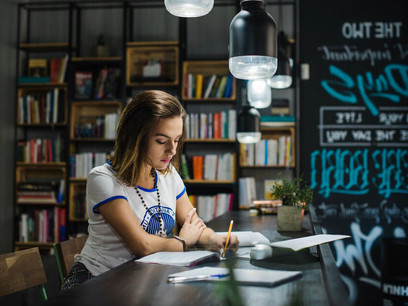 A focused student sitting at a table, writing in notebooks, driven by motivation to study