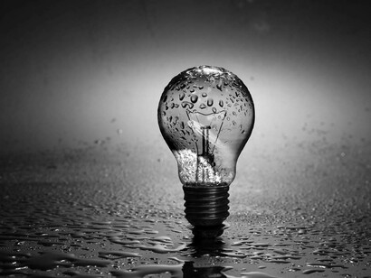 A lightbulb that has specks of watermarks on it and is around tiny puddles of water is not displaying signs of energy