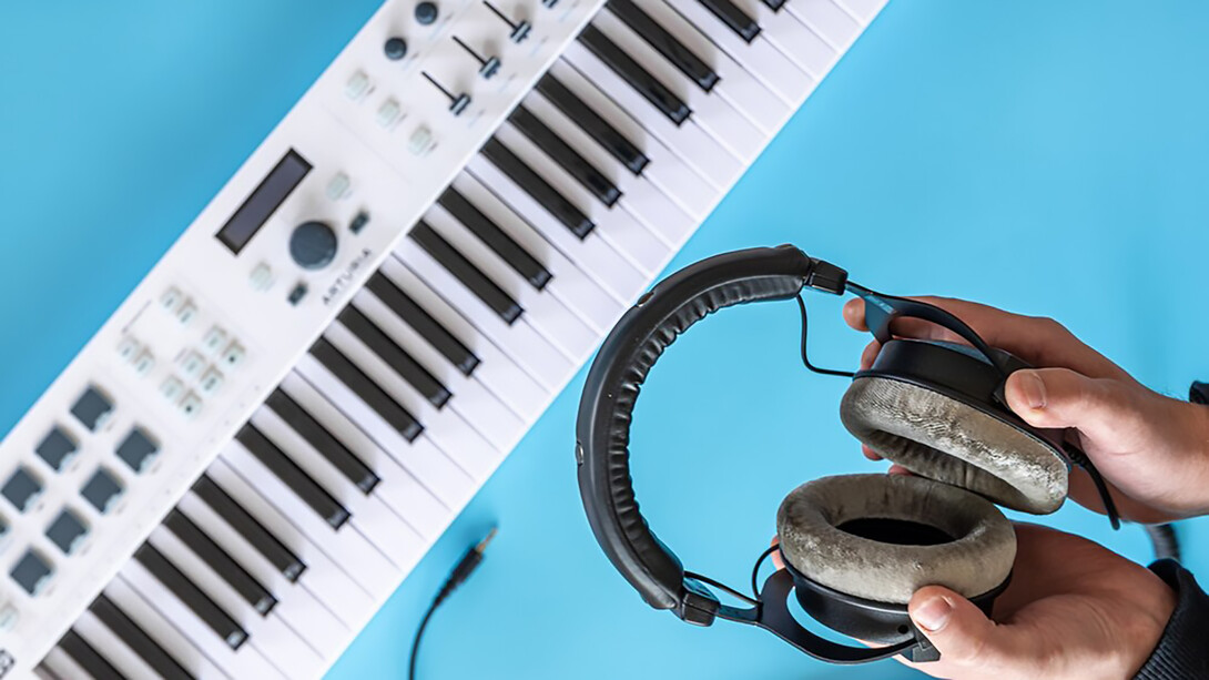 The essence of amapiano music with an image of headphones held by a male against a backdrop of musical keys and a piano, capturing the soulful rhythm and vibe of amapiano