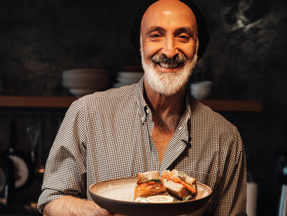 A middle-aged man presents a bowl of food with a smile on his face
