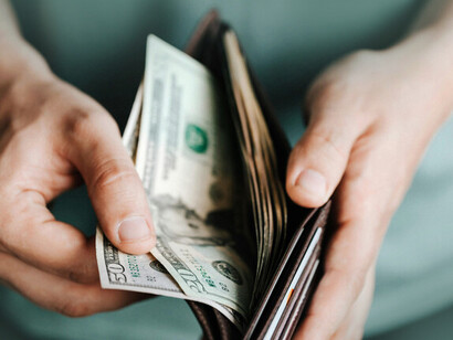A person taking US dollar bills from their wallet