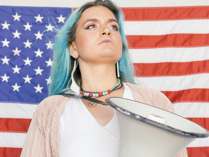 A young woman holding a speaker