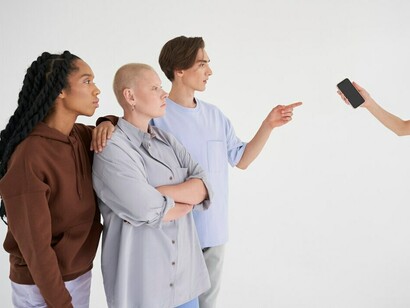 A group of individuals huddled together, fixated on a single phone screen, reflecting the grip of social media addiction