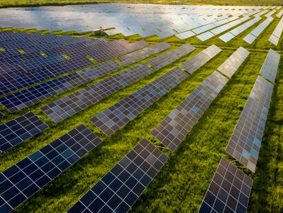Blue solar photovoltaic panels generating renewable, clean energy against a picturesque rural landscape with a stunning sunset backdrop