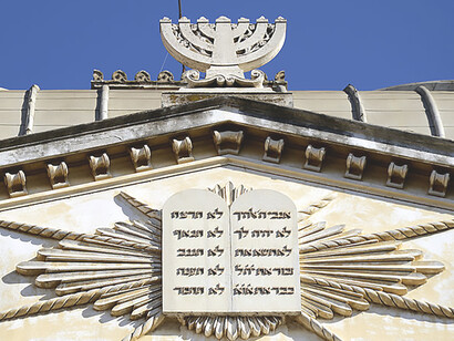 The Great Synagogue in Rome boasts exquisite features including a prominent Menorah and Tables of the Law, serving as iconic symbols of Jewish faith and cultural significance within the historical setting of the synagogue, Italy