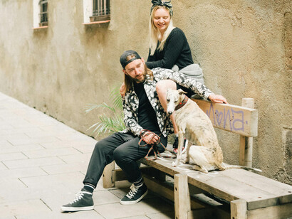 A couple an their dog sitting a bench in an inner street