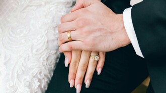 A close-up of a newly married couple’s clasped hands, representing the fragile beginning of a lifelong partnership