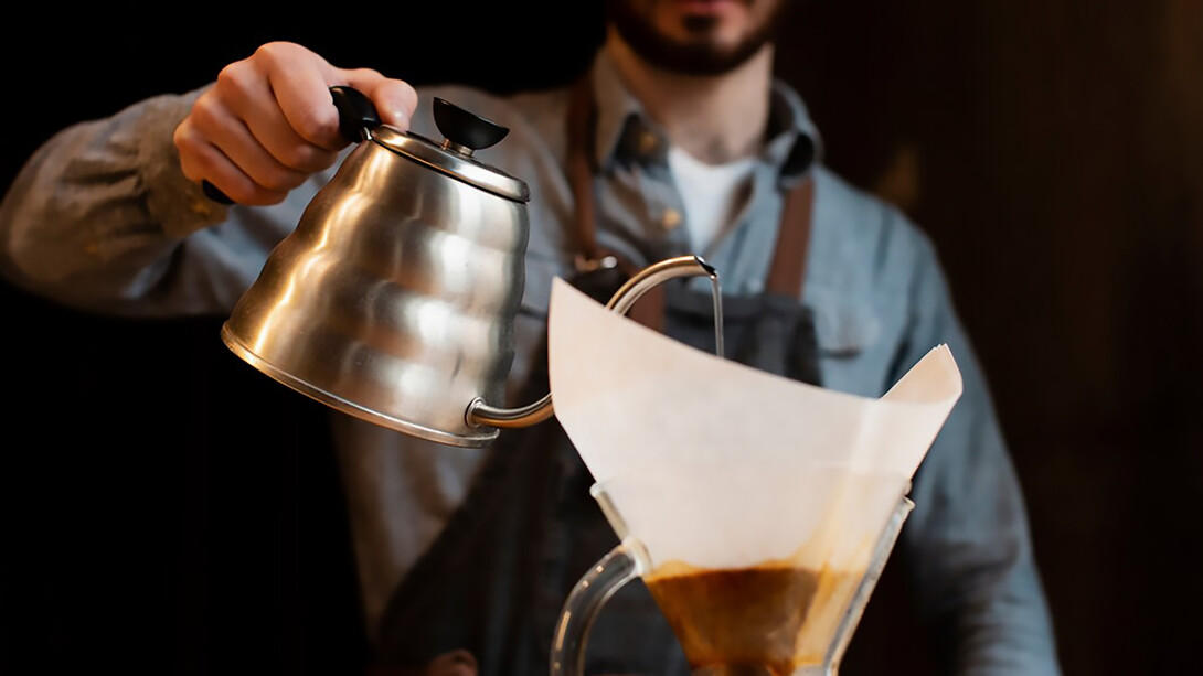 Man pouring coffee from a pot into a filter, demonstrating the roasting process
