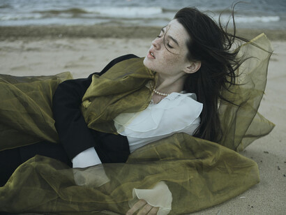 A reflective portrait of a woman laying on the sand