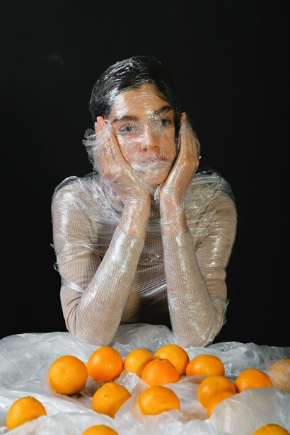 A person with plastic over their face and oranges. There is an ultra-processed food pandemic
