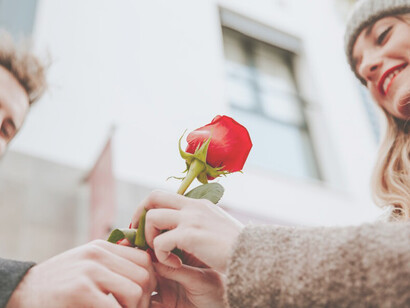 A joyful woman receives a rose from a man