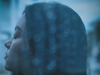 A reflective portrait of a young woman behind a glass