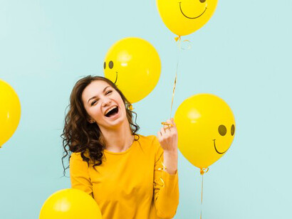 Smiling woman with cheerful balloons featuring smiley faces, highlighting the connection between positive thinking and mental health