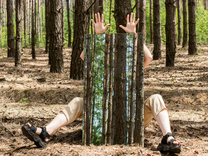 A person in the forest sitting down covered by a mirror