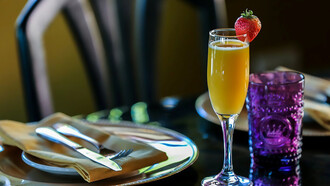 A champagne glass filled with a refreshing mimosa, accompanied by a vibrant brunch table set with delicious cocktails and food