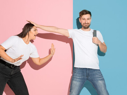 A young emotional couple against a pink and blue wall, symbolizing relationship dynamics and portraying the essence of a happy couple