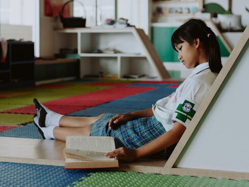 Girl sits down and reads her book at school, avoiding the temptation of distractions