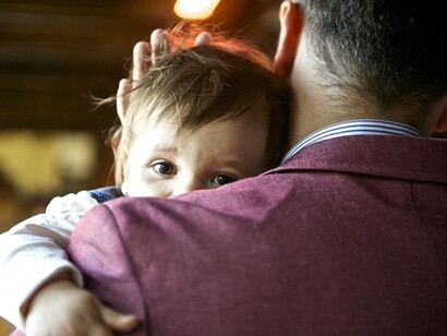 Un niño se refugia sobre el hombro de su padre