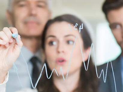 Serious businesswoman presenting a graph to her colleagues during a meeting, showcasing data analysis and collaborative decision-making in the workplace