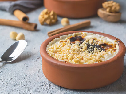 Turkish Sütlaç: baked rice pudding delight served in earthenware casserole, topped with hazelnuts
