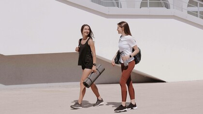 Two friends walk with yoga mats