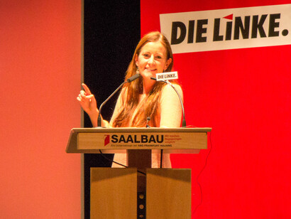 With the backdrop of recent election results, the speaker passionately addresses the audience about the challenges facing Germany and the need for a renewed leftist vision