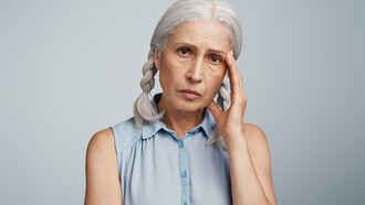 A senior woman with pigtails, dressed in a blue blouse, representing the experience of living with Alzheimer