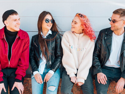 A group of young friends smiling and looking at each other, reflecting the close-knit relationships and positive interactions characteristic of millennials