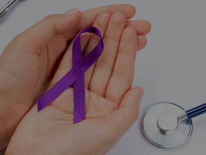 Hands holding a purple ribbon alongside a stethoscope