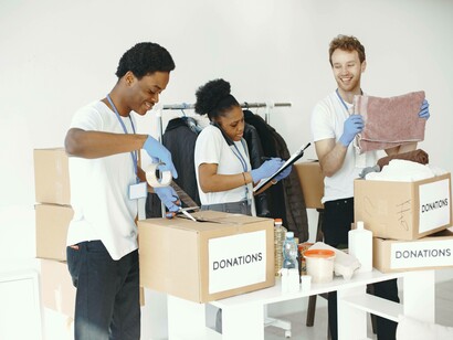 A trio helping put donations in cardboard boxes and feeling happy