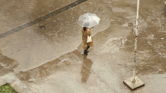 A woman walking alone through the city on a rainy day, sheltered beneath an umbrella