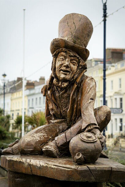 Las mentes más creativas sometidas a algún tipo de situación que origina fluctuación del estado de ánimo, un alto grado de originalidad. Alicia en el país de las maravillas. Estatua de madera. El sombrero Loco y su tetera en Llandudno, Gales, Reino Unido