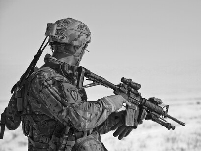 Black and wihite picture of a soldier preparing his gun, taken from behind