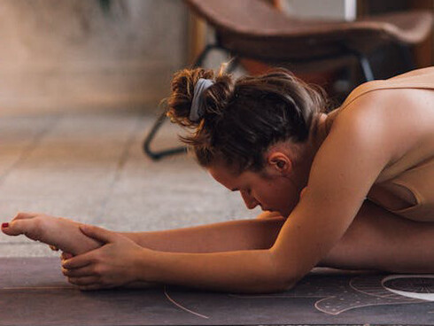 A woman stretching, calm and deep in focus, at one with herself and her surroundings