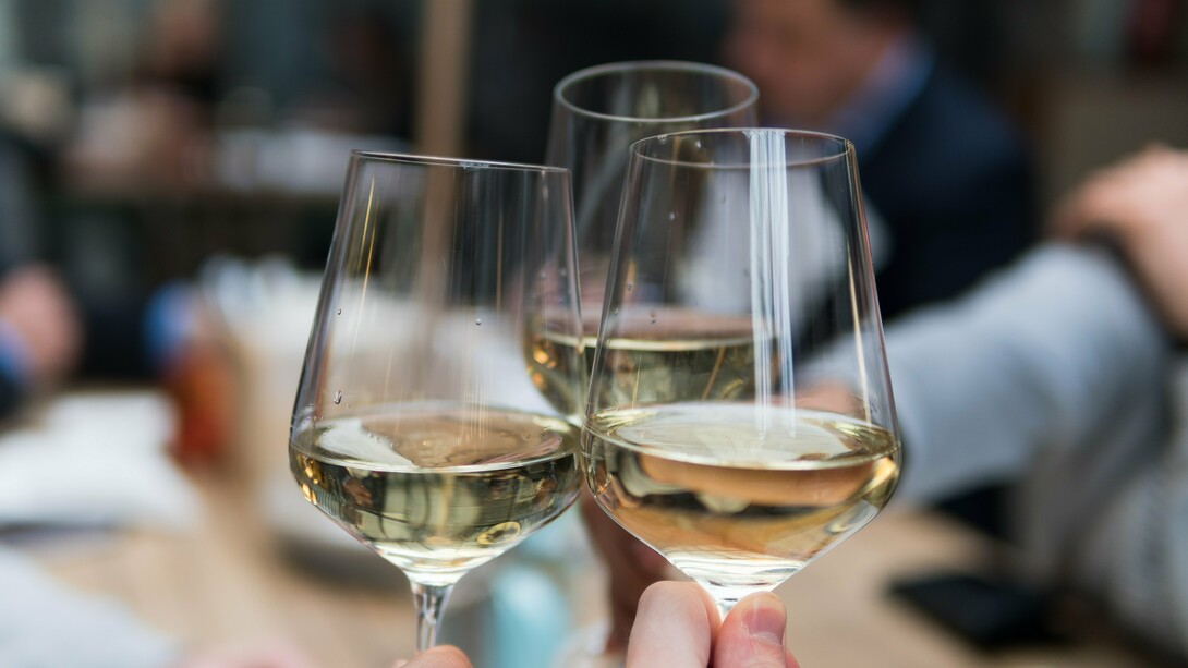 Three friends toast to a glass of white wine