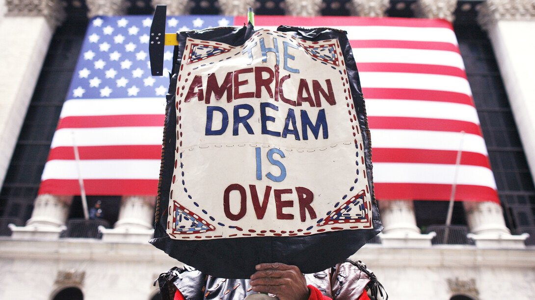 A protest sign of the American dream, in front of the American flag