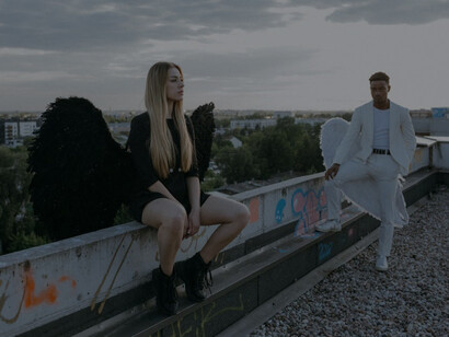 A man and woman dressed in contrasting black and white angel costumes symbolizing themes of good and evil