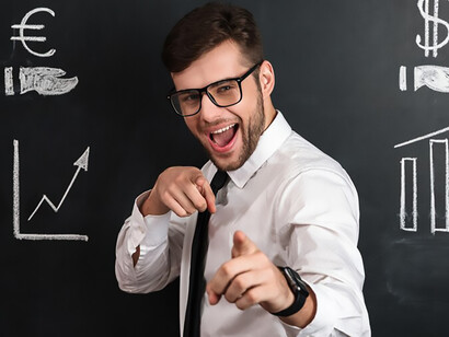 Confidently delivering a financial project, a young man in a white shirt stands before a blackboard adorned with symbols of euro and dollar, symbolizing expertise and innovation in finance