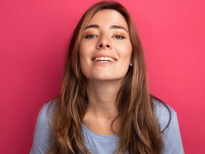 Young woman in a blue t-shirt, set against a pink background, showcasing oral health and hygiene