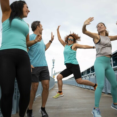 A group of energetic individuals in vibrant athletic wear enjoy an outdoor workout session, demonstrating the joy and creativity that can be found in exercising together