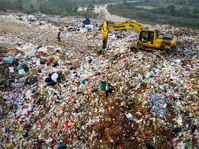 An large garbage dump, dangerously close to a river.