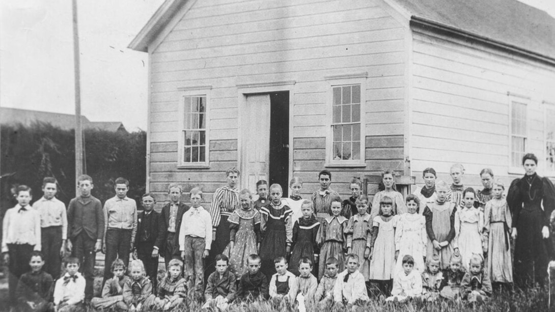 The Little Red School House in California, USA from long ago, with women as the teachers of different ages of children
