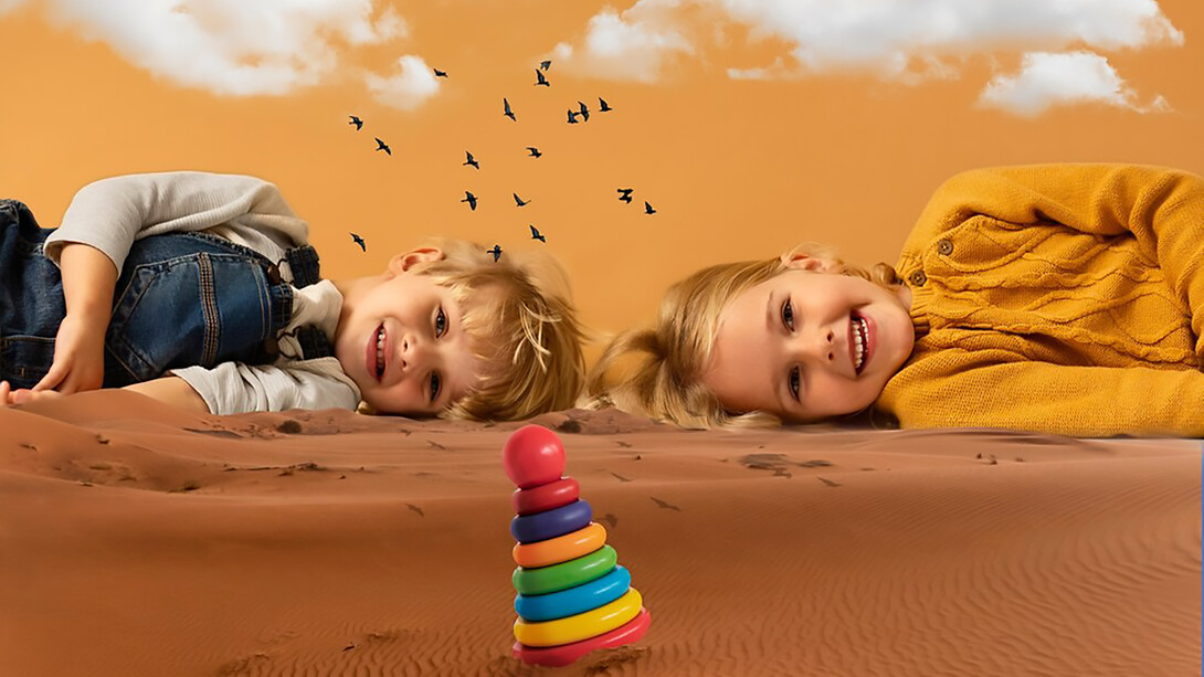 Two happy, independent children lying on the sand under a beautiful sky with clouds