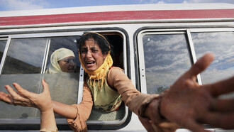 A distressed woman reaches out from a crowded bus, capturing a moment of urgency, separation, and human vulnerability amid crisis, Kashmir