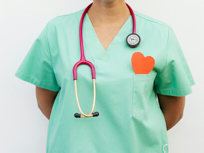 A nurse wearing a green shirt with a heart popping out from the pocket