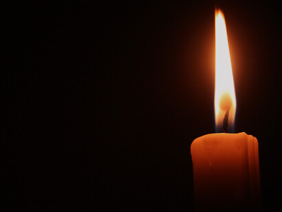 A candle burns brightly in the darkness