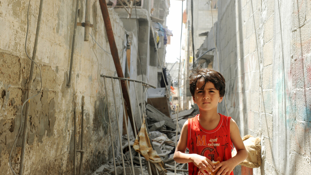 In the shadow of destruction, a child's resilience shines through, reminding us that hope persists even amidst chaos and despair