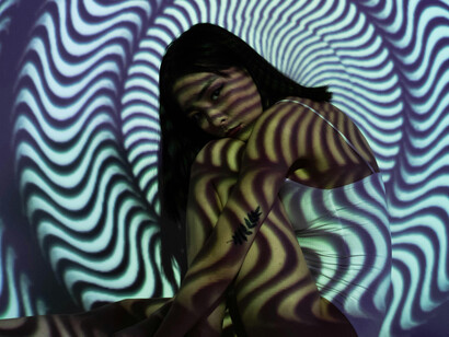 A woman hugging her legs as a hypnotic shade covers her