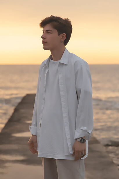 Amidst the sunset by the sea, a contemplative man stands, his thoughts drowning in the ebb and flow of the tranquil waves